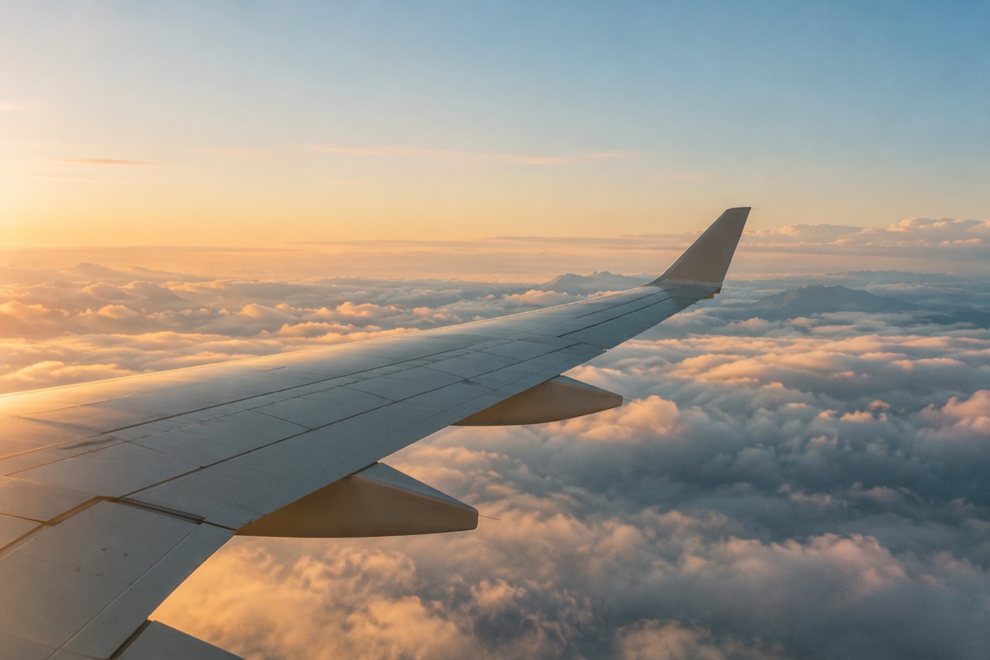 An airplane wing above clouds in the soft light of sunrise